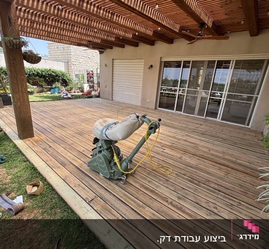 דק עץ עם מכונת ליטוש תחת פרגולה מעץ